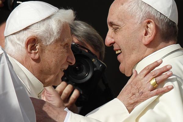 Pope Francis greets retired Pope Benedict XVI.